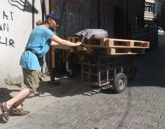 Sen with 3 wooden crates using a wagon lent to us approaches Taksim Square.